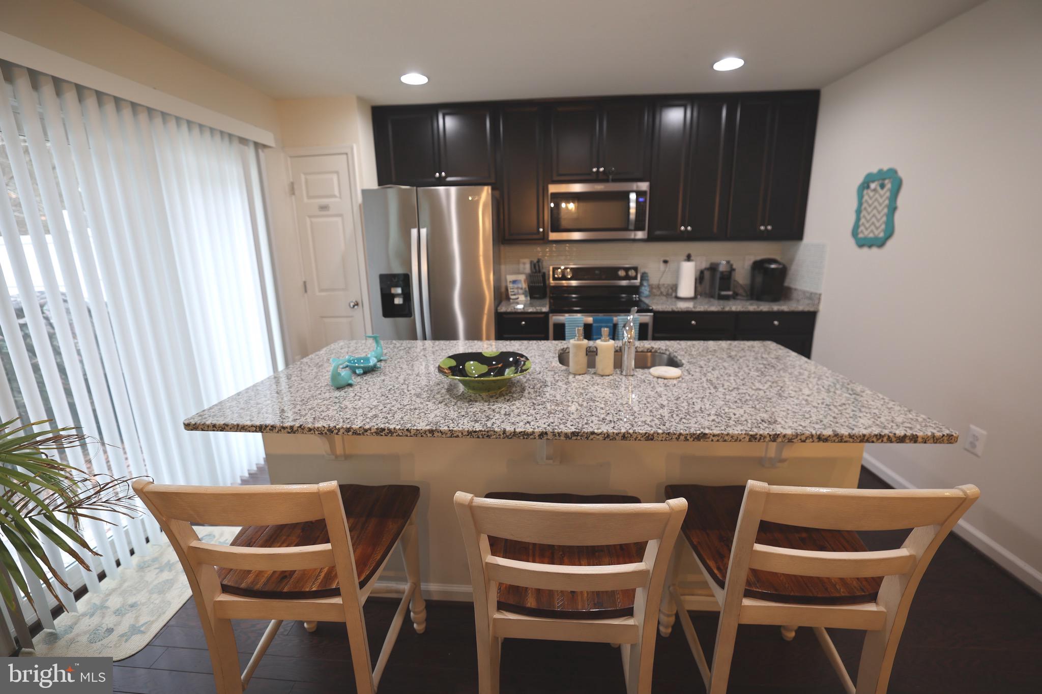 130 Intrepid Lane Berlin, MD 21811 - Photo 7 of 18 a kitchen with granite countertop kitchen island stainless steel appliances a dining table and chairs