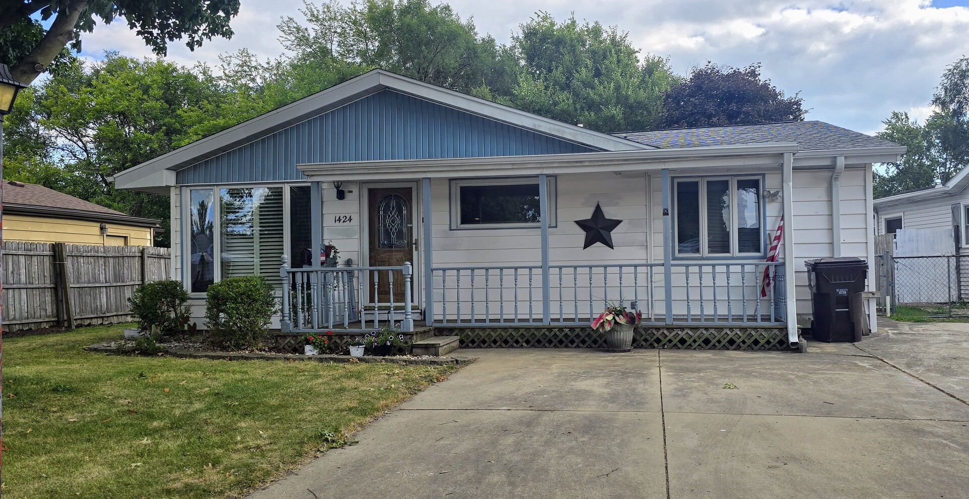 a view of a house with a yard plants and large tree