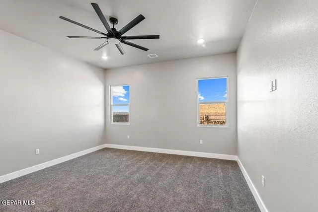an empty room with windows and ceiling fan