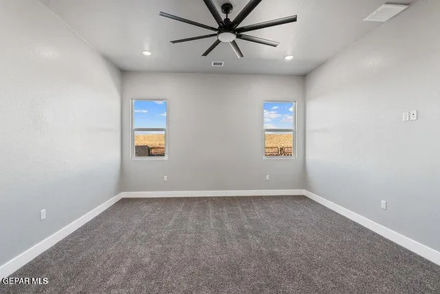 an empty room with windows and fan