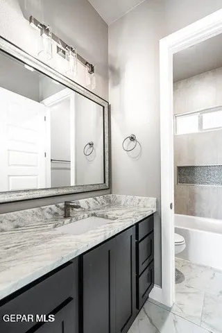 a bathroom with a granite countertop sink a toilet and a mirror