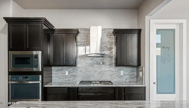 a kitchen with kitchen island granite countertop a refrigerator and a stove top oven