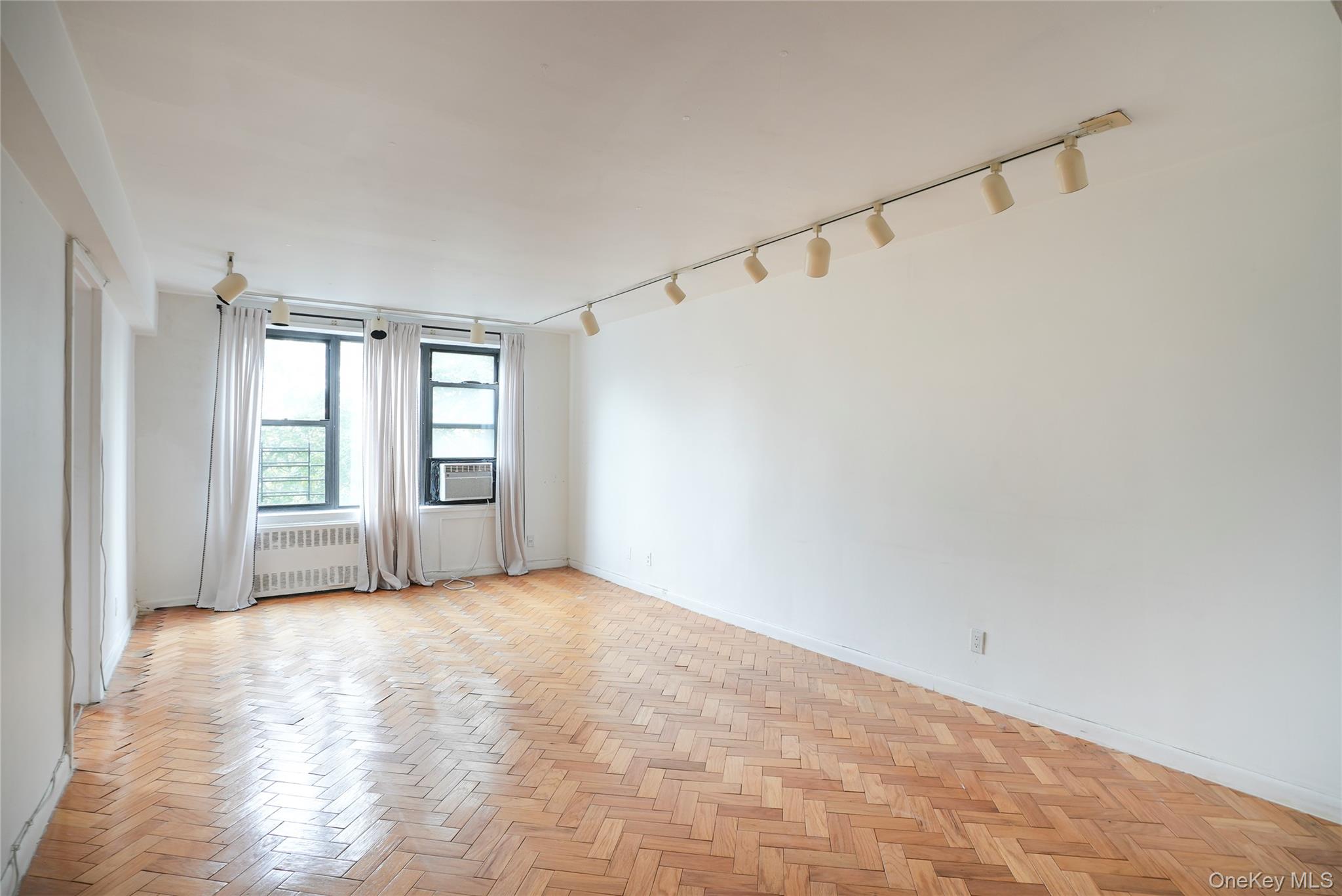 Empty room with rail lighting and radiator heating unit