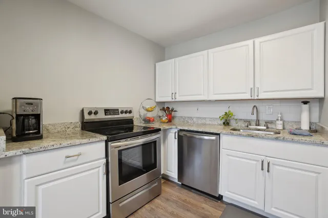 a kitchen with granite countertop cabinets stainless steel appliances and wooden floor