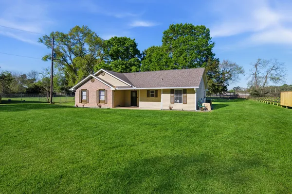 a view of a house with a big yard and large trees