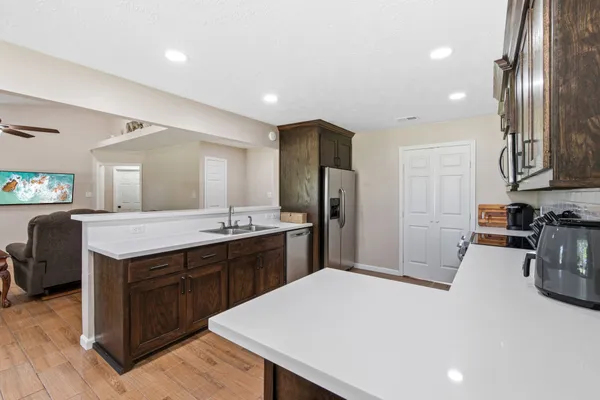 a kitchen with stainless steel appliances granite countertop a refrigerator a sink dishwasher a dining table and chairs with wooden floor