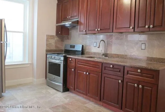a kitchen with granite countertop a sink cabinets and stainless steel appliances