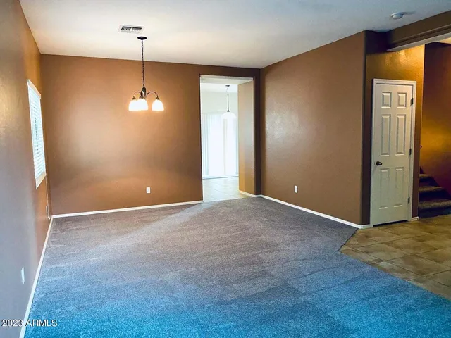 a view of an empty room with window and chandelier