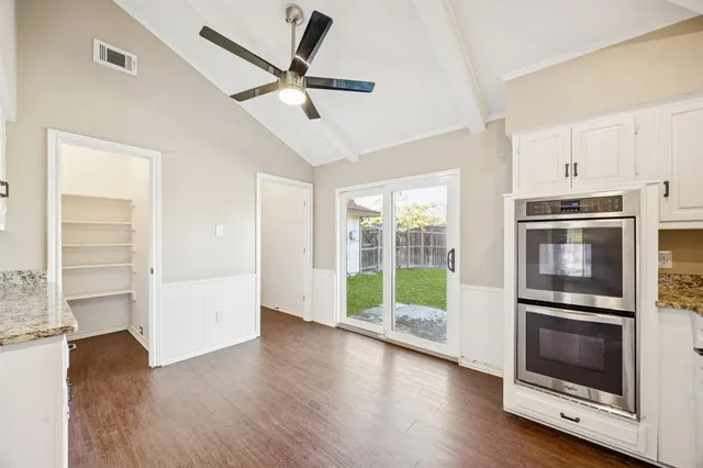 a open kitchen with white cabinets and wooden floor