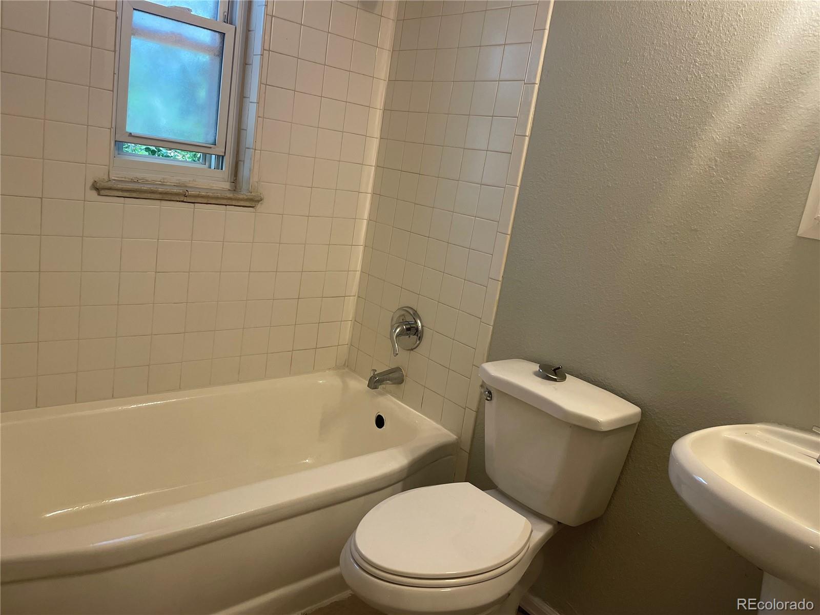 1528 Ulster Street Denver, CO 80220 - Photo 8 of 8 a white toilet and a bath tub sitting next to a white sink