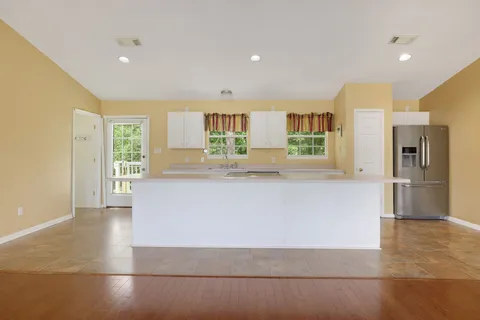 a large white kitchen with kitchen island a refrigerator and a sink