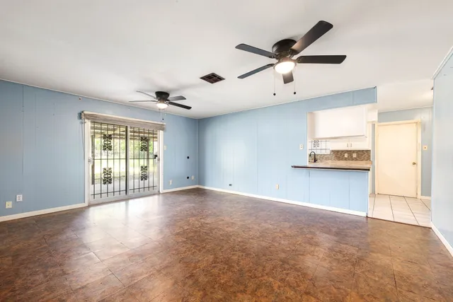 an empty room with a window and a fan