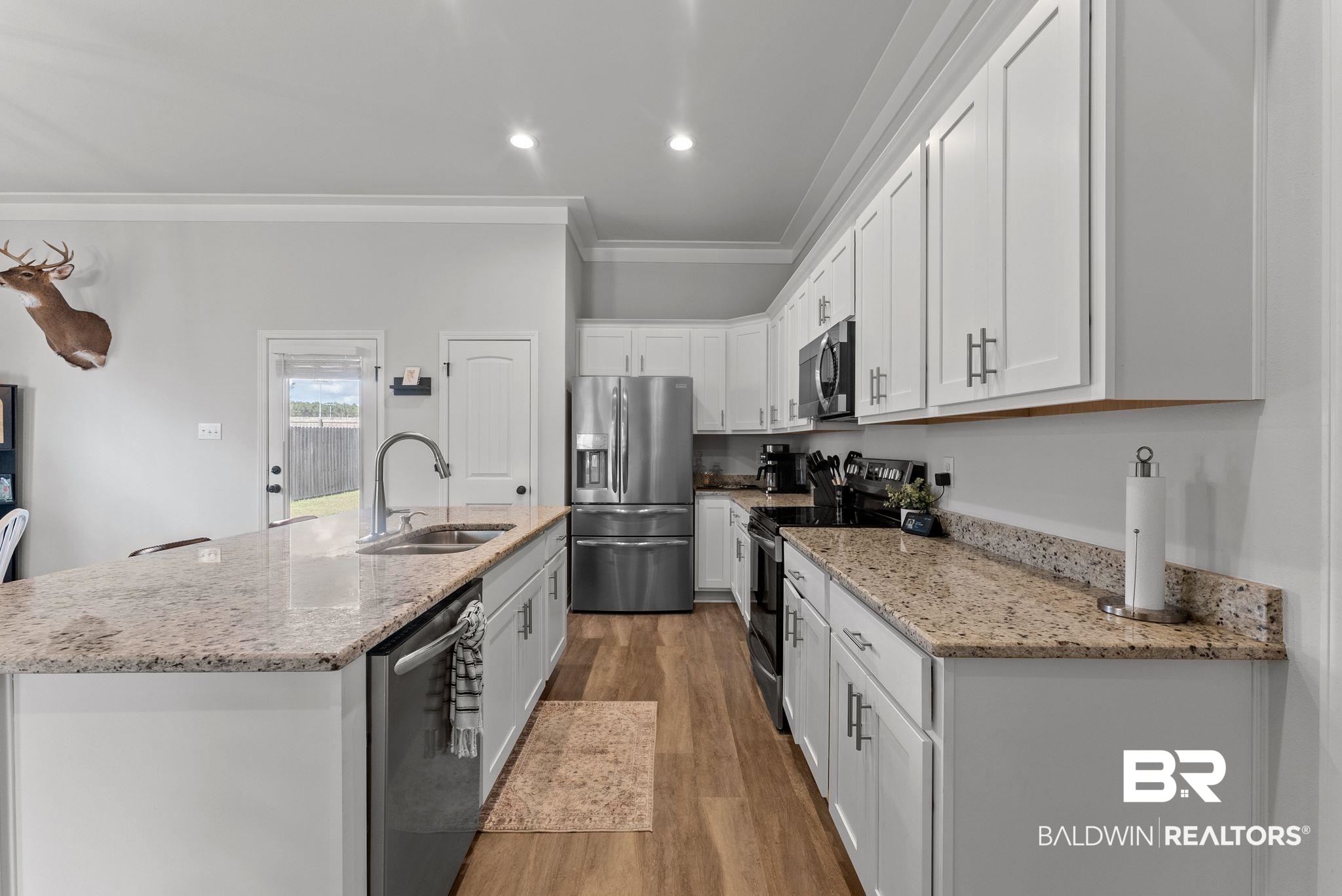 10745 Brodick Loop Daphne, AL 36527 - Photo 12 of 39 Kitchen with white cabinetry, stainless steel appliances, light stone countertops, an island with sink, and crown molding