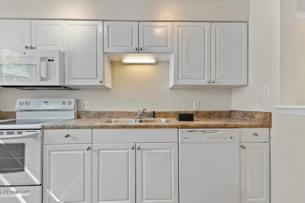 a kitchen with granite countertop white cabinets and a sink