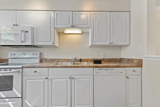 a kitchen with granite countertop white cabinets and a sink