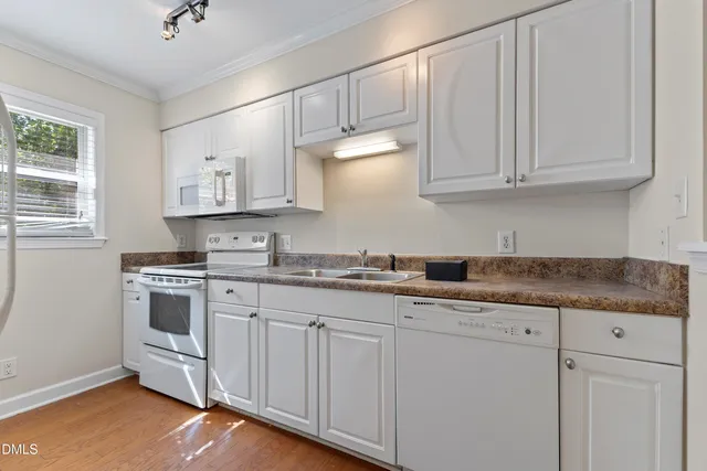 a kitchen with granite countertop white cabinets and white appliances