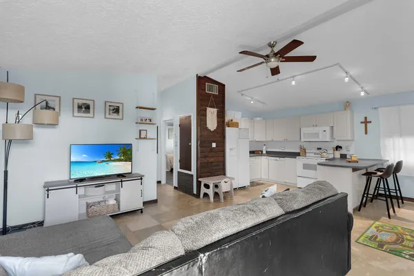 a living room with stainless steel appliances kitchen island granite countertop furniture and a flat screen tv