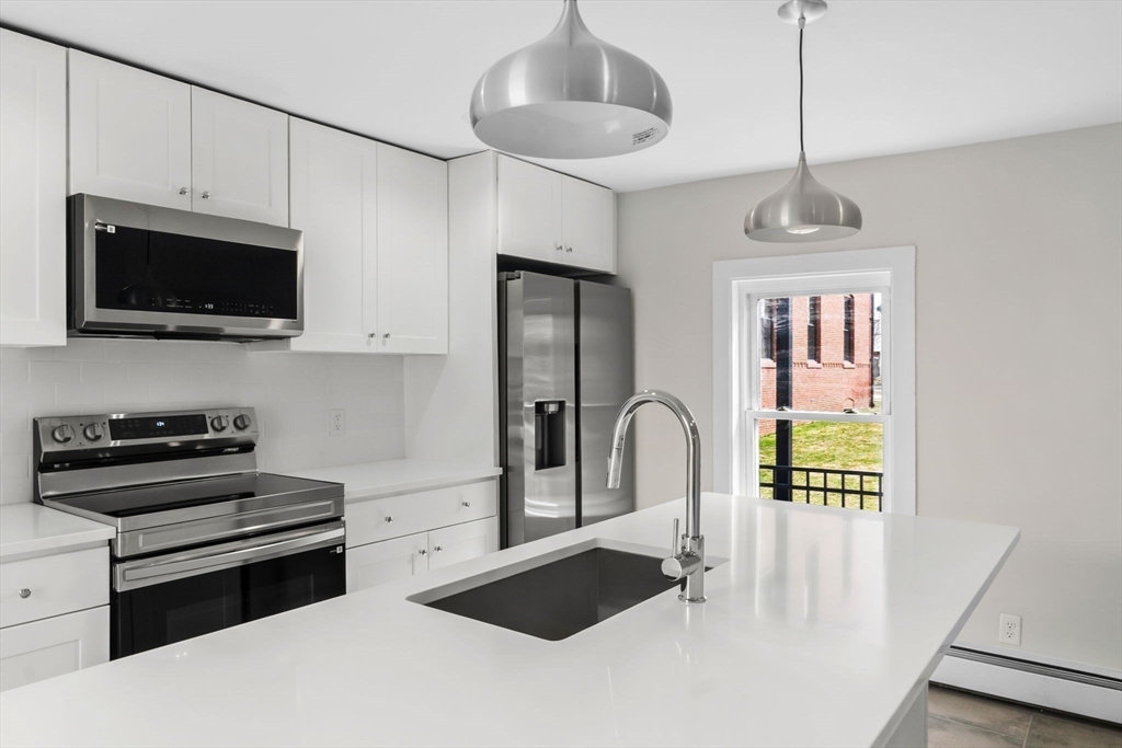 a kitchen with stainless steel appliances granite countertop a stove a sink and a microwave