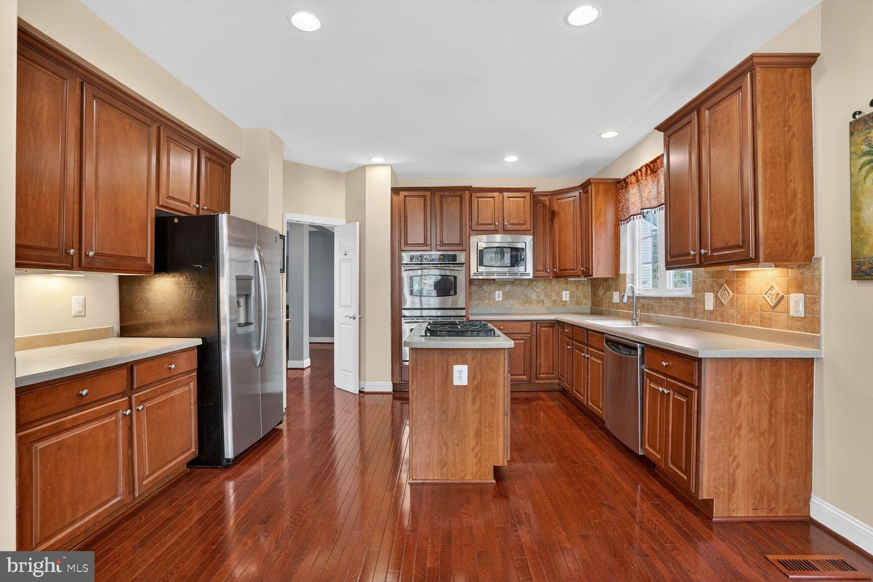 3308 McCorkle Court Triangle, VA 22172 - Photo 21 of 82 a kitchen with stainless steel appliances granite countertop wooden cabinets a refrigerator a sink a stove a refrigerator and wooden floors