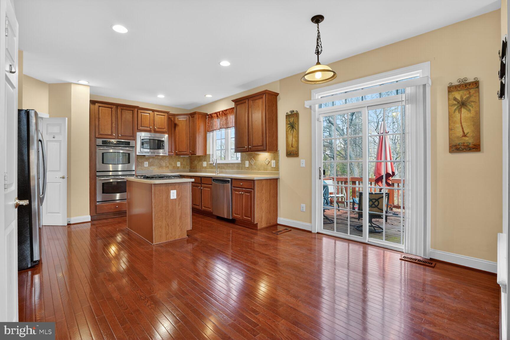 3308 McCorkle Court Triangle, VA 22172 - Photo 24 of 82 a kitchen with stainless steel appliances granite countertop a refrigerator a sink dishwasher a stove and a dining table with wooden floor