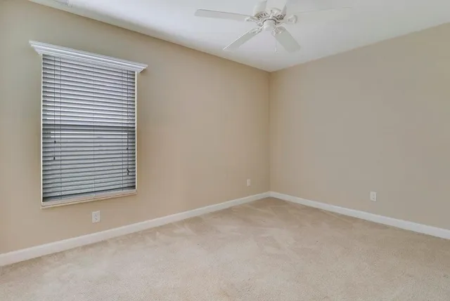 an empty room with a window and a fan