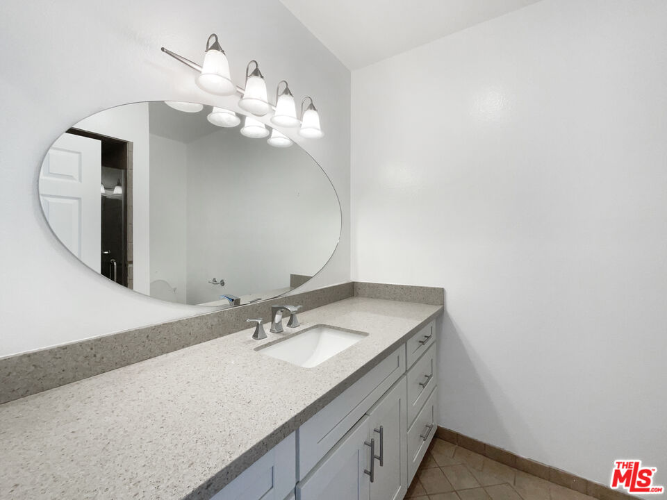 6864 Hatillo Avenue, Unit E Winnetka, CA 91306 - Photo 13 of 18 a bathroom with a sink vanity and mirror