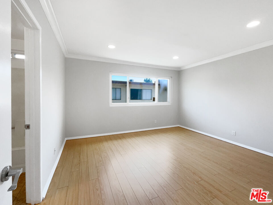 6864 Hatillo Avenue, Unit E Winnetka, CA 91306 - Photo 14 of 18 an empty room with wooden floor and windows