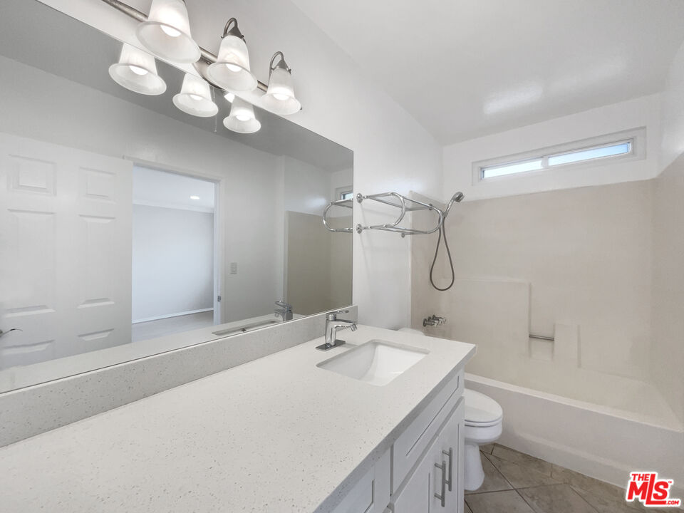 6864 Hatillo Avenue, Unit E Winnetka, CA 91306 - Photo 16 of 18 a bathroom with a sink a toilet and a large mirror
