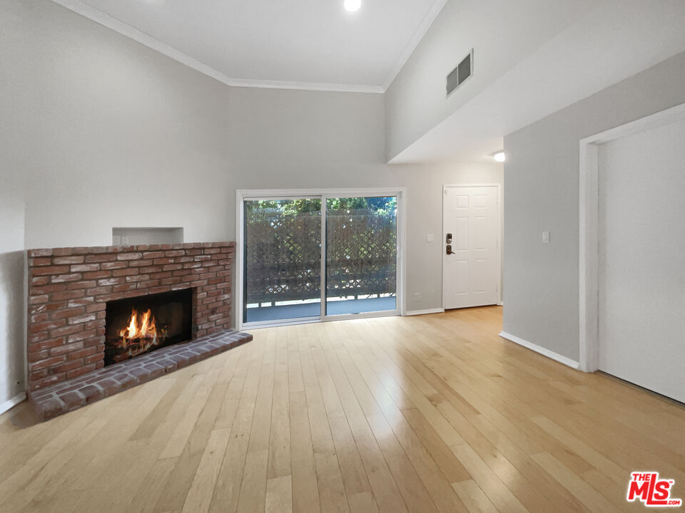 6864 Hatillo Avenue, Unit E Winnetka, CA 91306 - Photo 3 of 18 a view of an empty room with wooden floor fireplace and a window