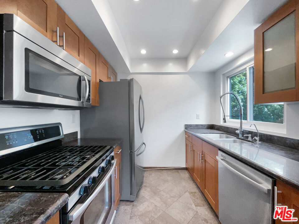 6864 Hatillo Avenue, Unit E Winnetka, CA 91306 - Photo 9 of 18 a kitchen with stainless steel appliances granite countertop a stove and a microwave