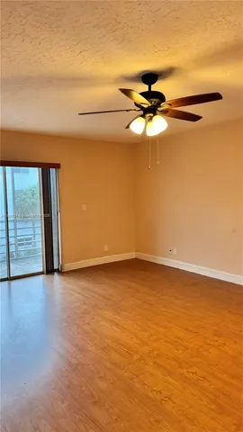 a view of a big room with wooden floor and a chandelier fan
