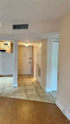 a view of a hallway with wooden floor and a bathroom