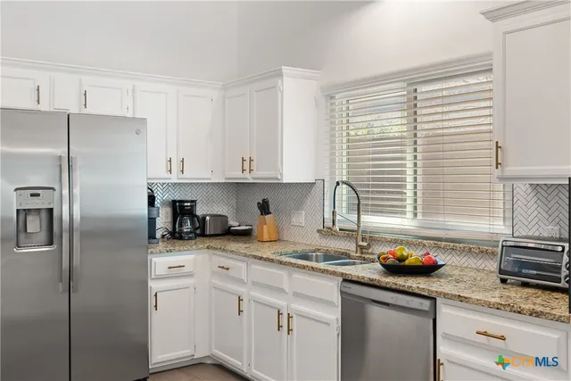 a kitchen with stainless steel appliances granite countertop a sink a refrigerator and cabinets