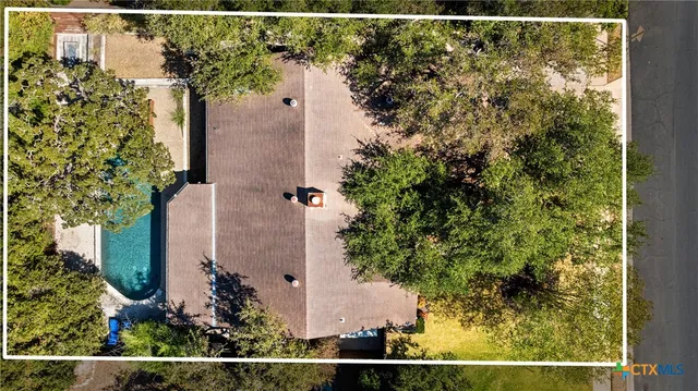 an aerial view of a residential houses with outdoor space and trees