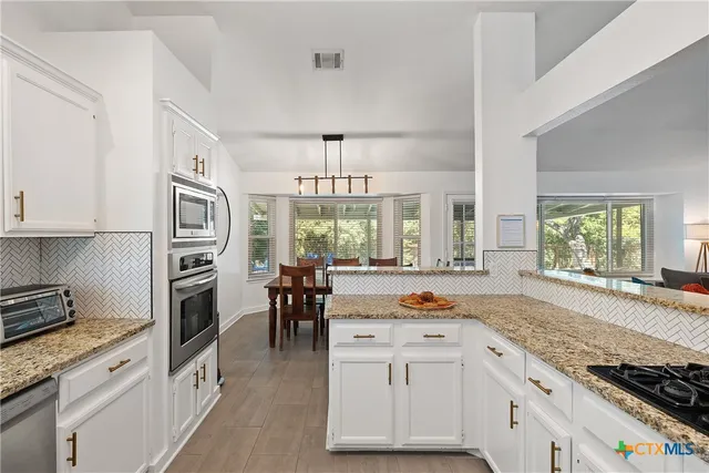a kitchen with stainless steel appliances granite countertop a stove and more cabinets