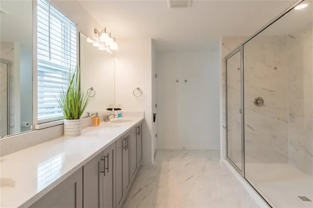 a bathroom with a double vanity sink mirror and shower