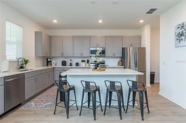 a kitchen with stainless steel appliances a table chairs refrigerator and a sink