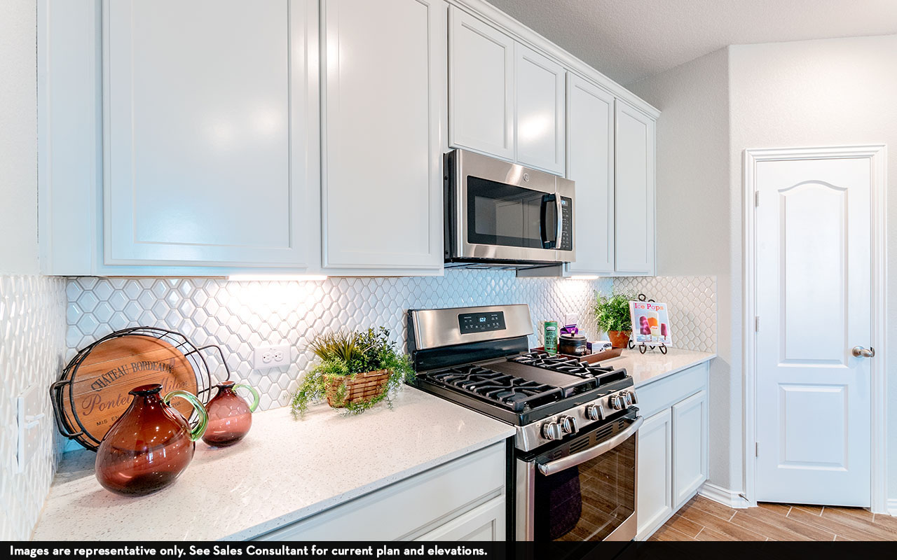 525 Lost Tree Drive Buda, TX 78610 - Photo 8 of 20 Kitchen featuring stainless steel appliances, light stone counters, white cabinets, and tasteful backsplash