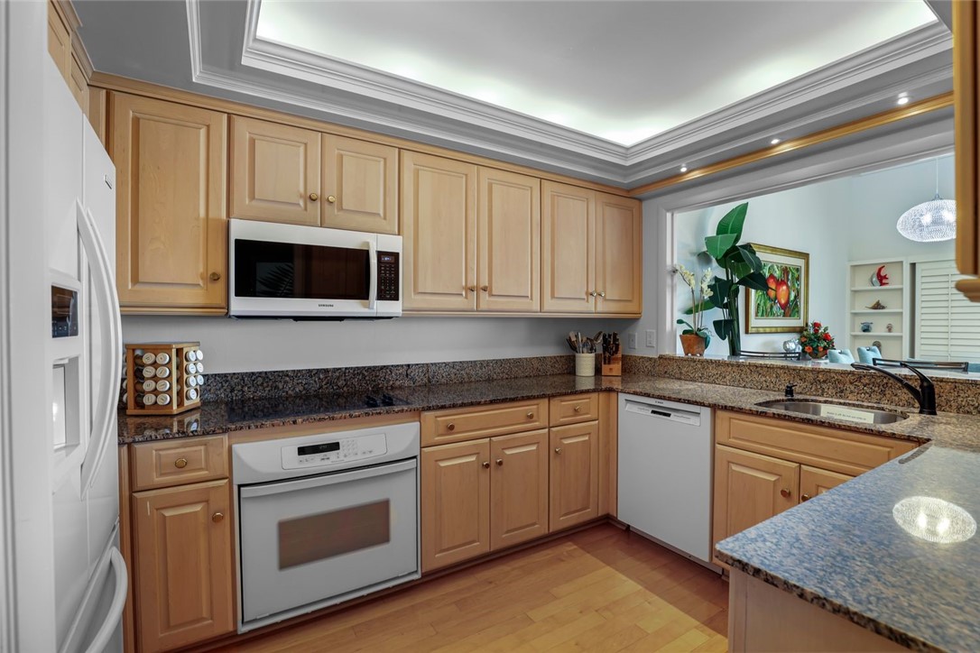 1001 Bay Road, Unit 302 Vero Beach, FL 32963 - Photo 11 of 31 a kitchen with stainless steel appliances granite countertop a sink and cabinets with wooden floor