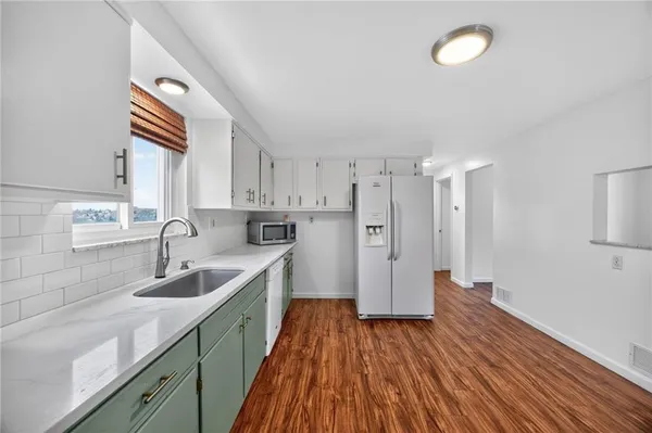 a kitchen with sink a refrigerator and wooden floor