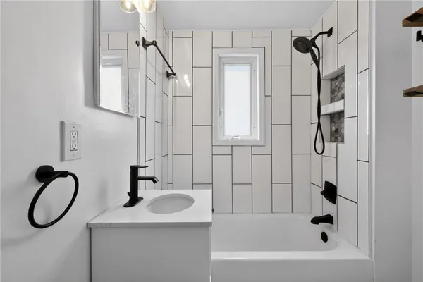 a bathroom with a granite countertop sink a mirror and shower