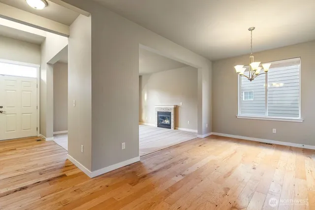 an empty room with wooden floor chandelier and windows