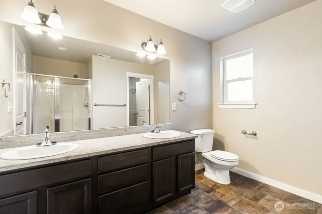 a bathroom with a double vanity sink a toilet and a mirror