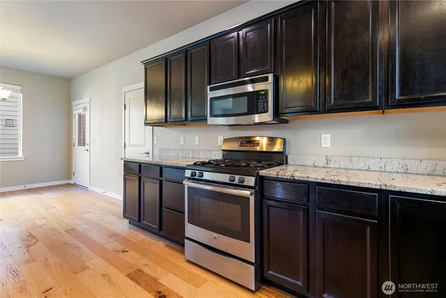 a kitchen with stainless steel appliances granite countertop wooden cabinets a stove top oven a sink and dishwasher