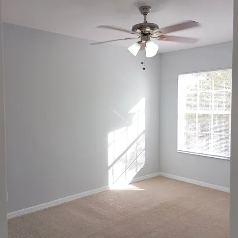 an empty room with windows and chandelier fan