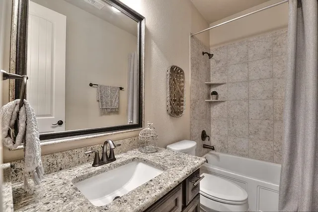 a bathroom with a granite countertop sink toilet mirror and shower