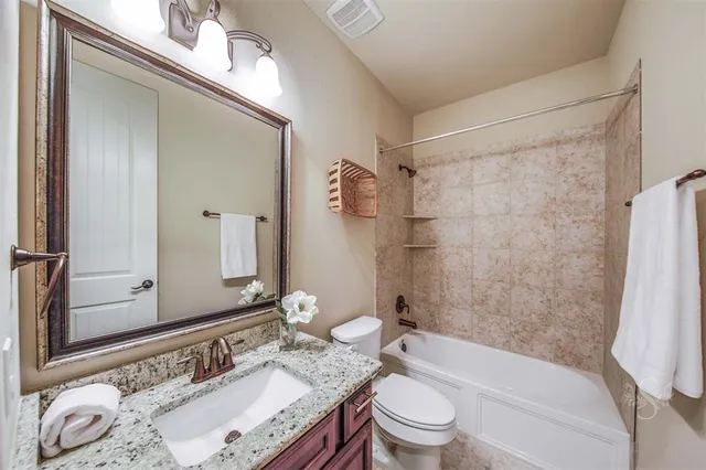 a bathroom with a granite countertop sink toilet tub and shower
