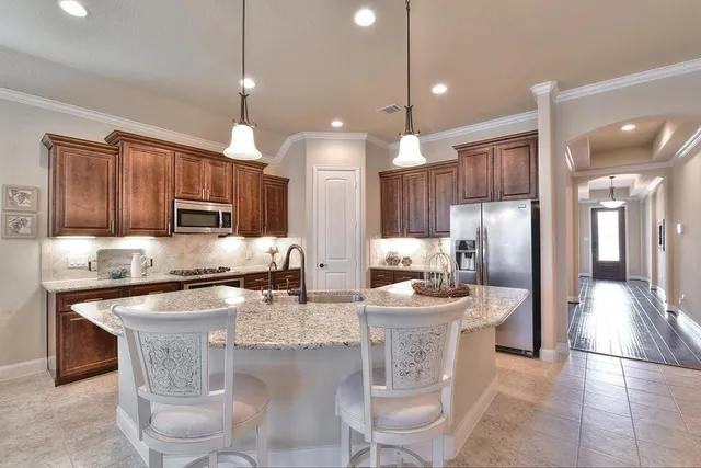 a kitchen with stainless steel appliances kitchen island granite countertop a sink a stove a refrigerator cabinets and chairs