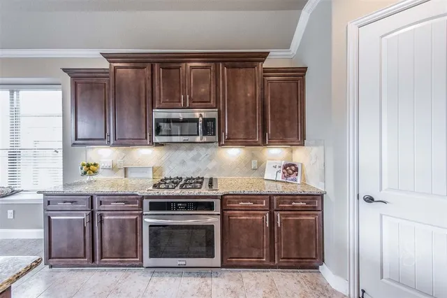 a kitchen with stainless steel appliances granite countertop wooden cabinets and a stove top oven