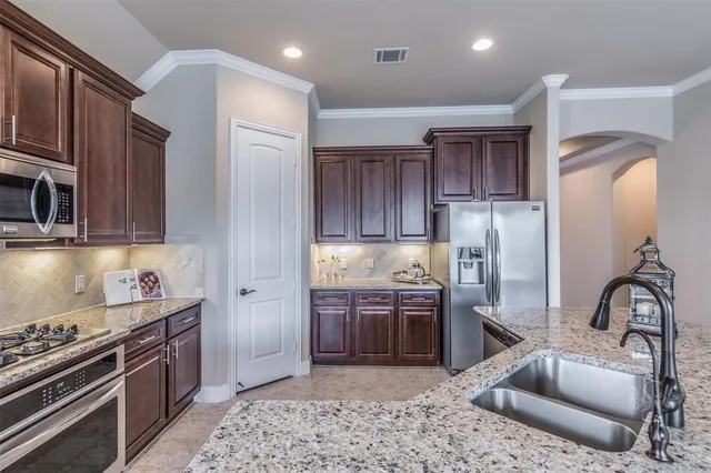 a kitchen with stainless steel appliances granite countertop a stove a sink and a refrigerator